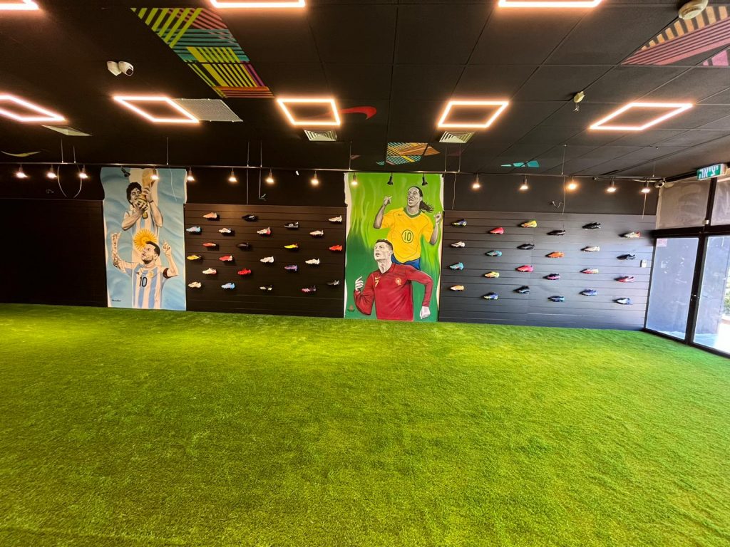 תמונה של סניף כרמיאל ספורט ישיר קיר נעלי כדורגל רצפה דשא ירוק